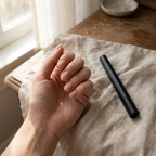 Hand with painted nails beside the nail polish pen